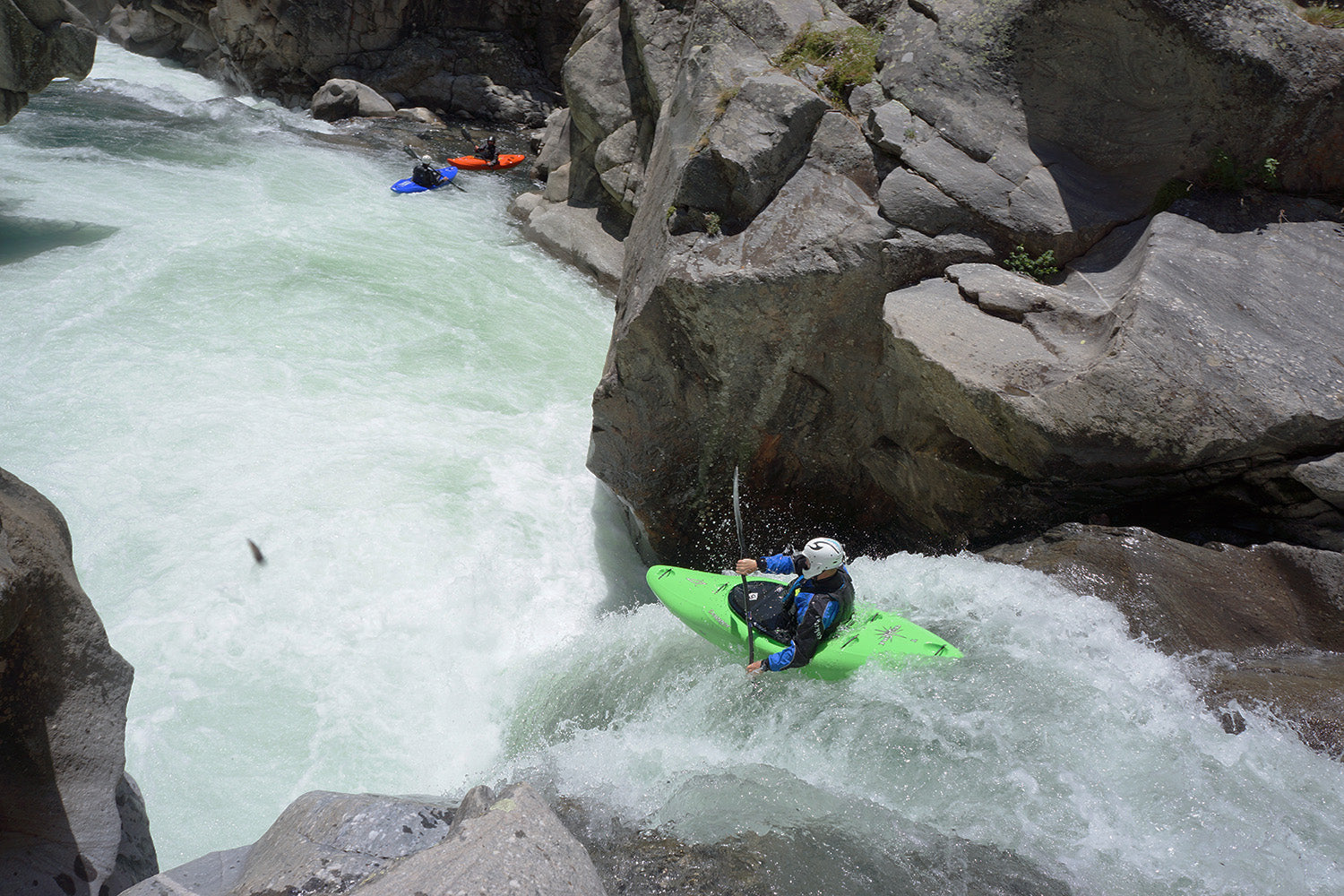 a man riding a green kayak on top of a river.