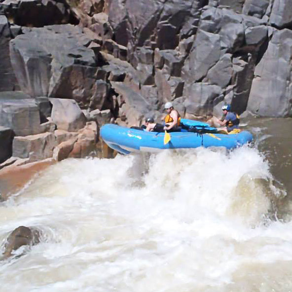 a group of people riding on top of a raft down a river.