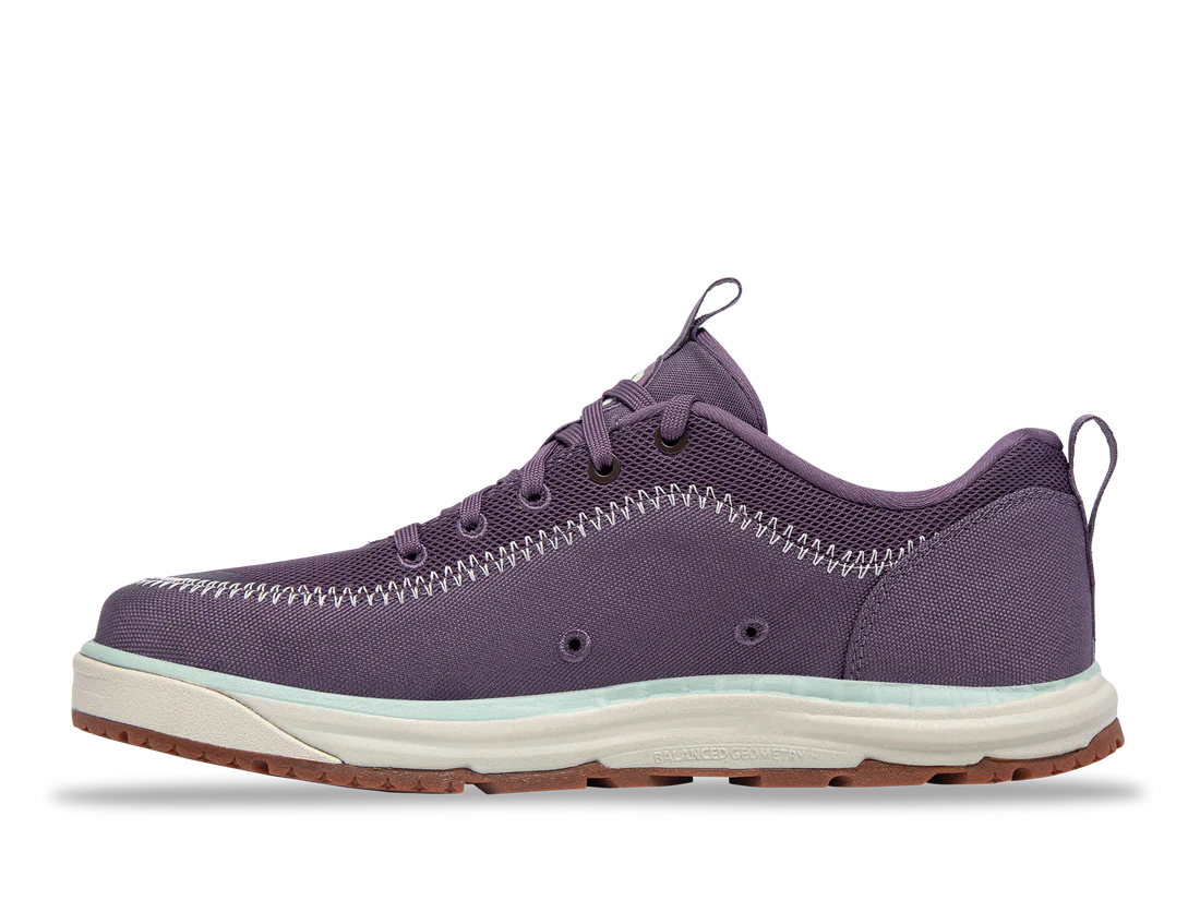 Astral's Brewer 3.0 is a purple sneaker made from hydrophobic canvas, featuring white stitching, a white sole, and brown tread. Designed for kayakers, it has laces and pull tabs for easy wear, offering style and functionality on the water and land.