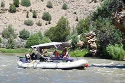 a group of people riding in a boat on a river.