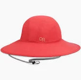 The Outdoor Research Oasis Sun Sombrero, a wide-brimmed red hat with chin strap and "OR" logo, provides UPF 50+ sun protection and is shown against a white background.