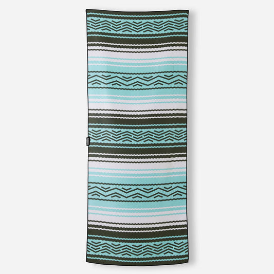 The Nomadix Original Towel is a rectangular sand-resistant beach towel with geometric patterns, horizontal stripes in black, white, blue, and light teal, plus a small black loop on one side.