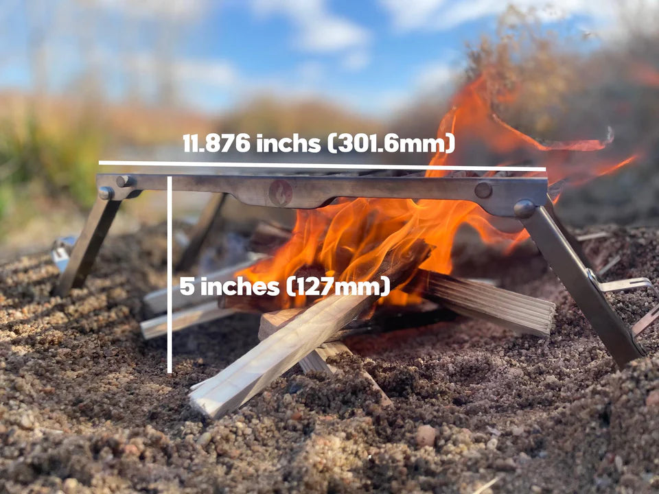 A VolCanNo Trident Combo camp stove from LavaBox stands on the ground, with a fire roaring in its center.