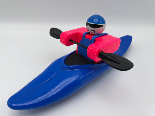 Introducing the Foamie Half-Slice from the Foamie Friends collection—this toy figure features a kayaker in pink and blue attire with a black paddle, seated in a blue kayak. It beautifully encapsulates the excitement of river adventures against a simple background.