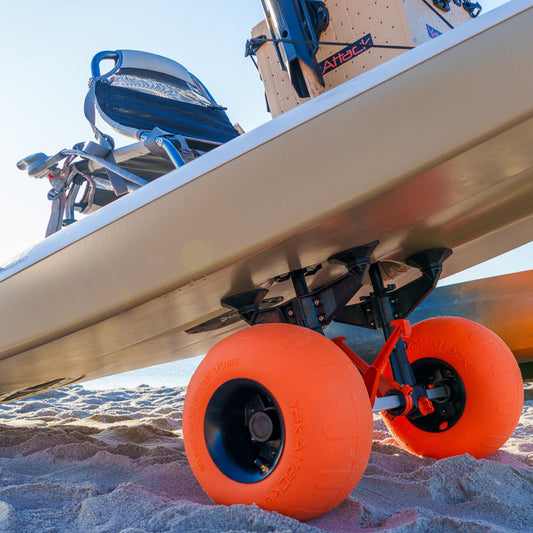 Close-up of a kayak on sand using the YakAttack TowNStow Scupper Kayak Cart with large sand wheels and adjustable scupper uprights for easy transport.