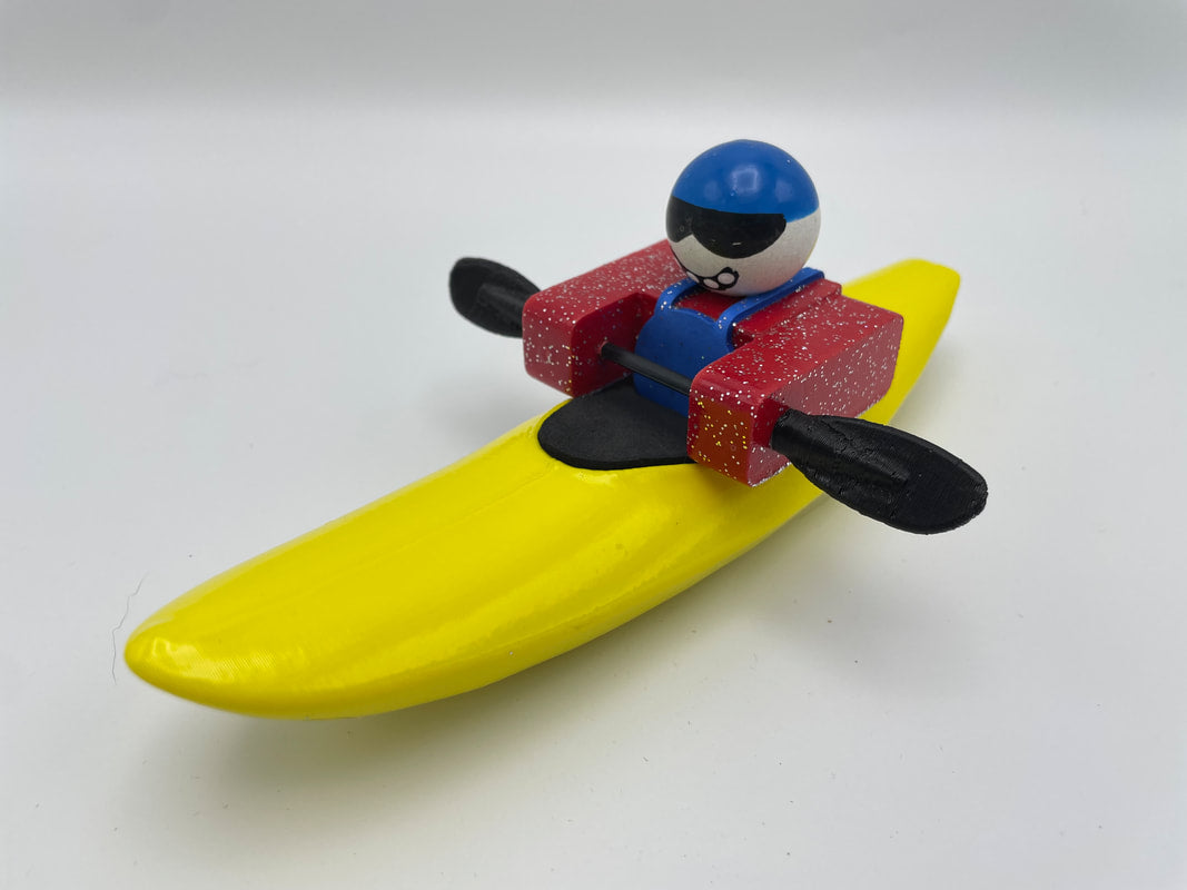 The Foamie Mini Creeker from the Foamie Friends series features a toy figure dressed in a red kayak outfit, holding paddles while seated on a yellow banana-shaped base. It's ideal for river play adventures with its delightful design and imaginative charm.