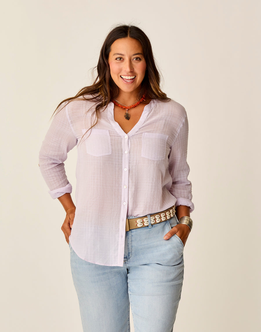 A woman with long dark hair wears the Carve Dylan Textured Shirt in light purple, paired with light blue jeans, a patterned belt, necklace, and bracelet, standing against a plain background.