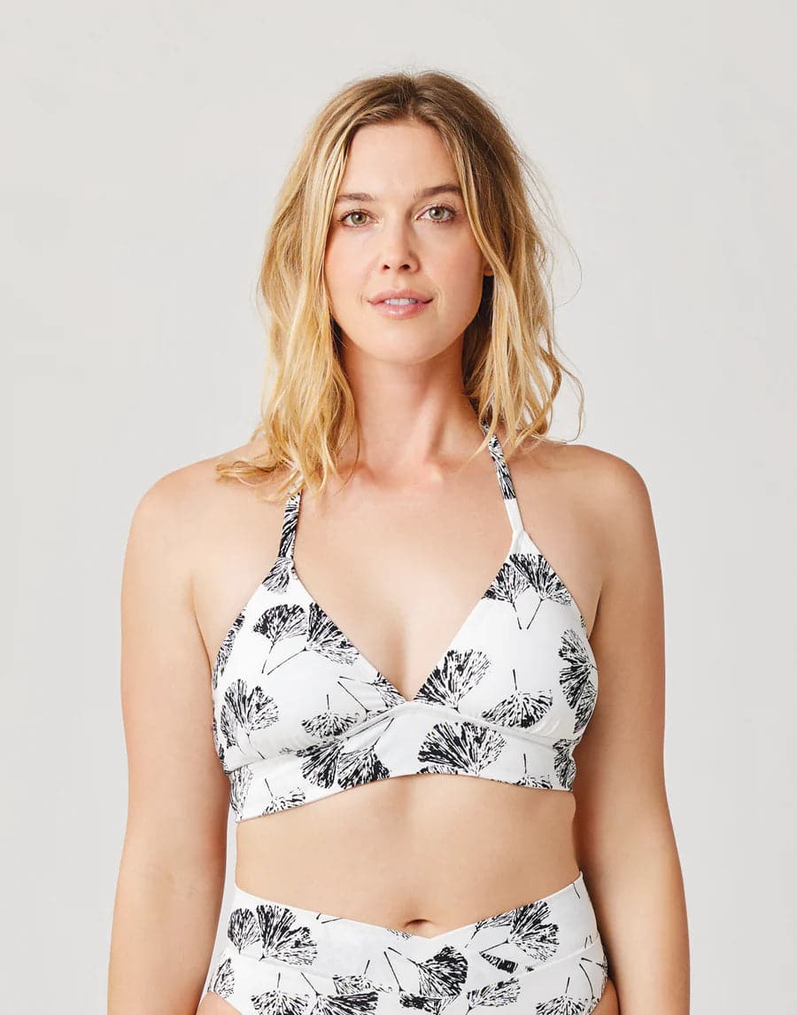 A woman wearing a Carve Dahlia Top with a floral print bikini.
