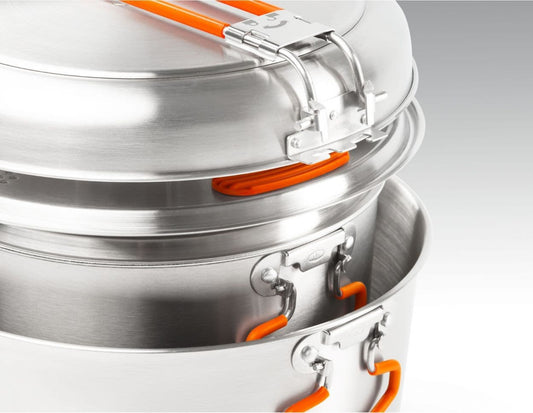 The Glacier Base Camper by GSI Outdoors features stackable aluminum pots with orange handles and latches, ideal for gourmet wild cooking and a perfect addition to your stainless cookware collection.
