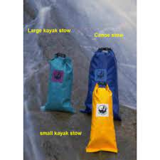 Featuring Jacks Plastic Welding's Kayak Stow made from durable PVC-coated polyester in large teal, along with a blue canoe stow and a small yellow dry bag for kayaking, all displayed against a natural backdrop.