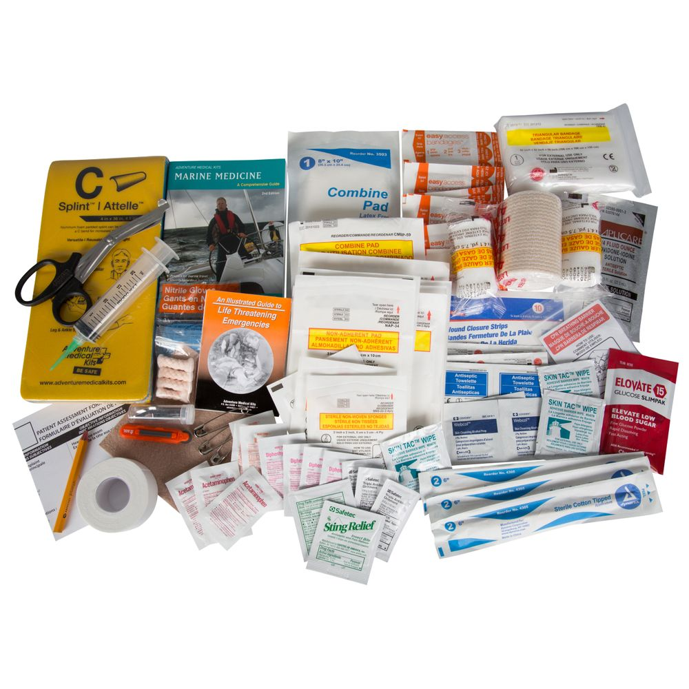 A spread of various first aid supplies, including bandages, gauze, medical tape, scissors, wound dressings, antiseptic wipes, and instruction booklets, arranged on a white surface.