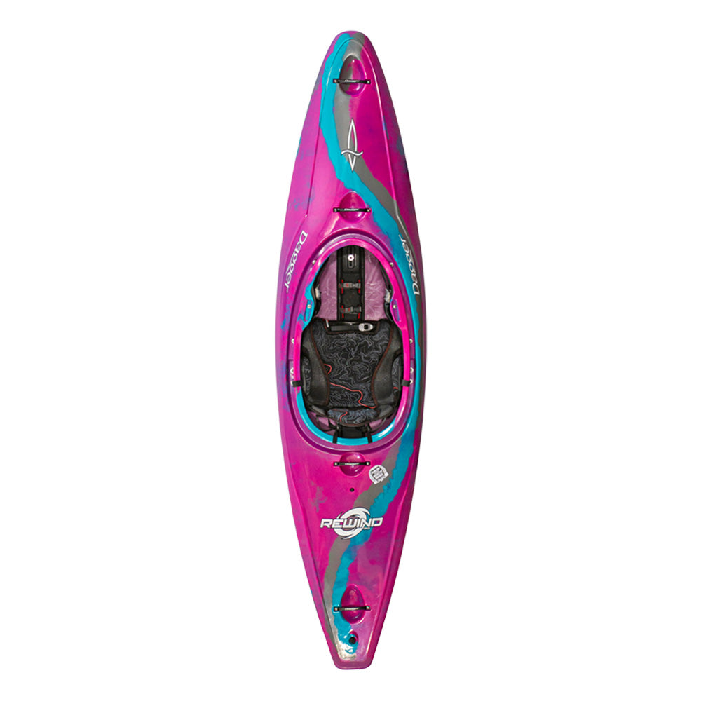 An overhead view of a brightly colored kayak, predominately pink with teal and gray accents. The kayak has a seat in the center and various attachments for paddling gear.
