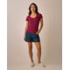 A woman faces forward, wearing a pink and navy striped t-shirt, Carve Oahu 4" Shorts in organic cotton, and white sneakers. She has one hand in her pocket and a neutral expression.