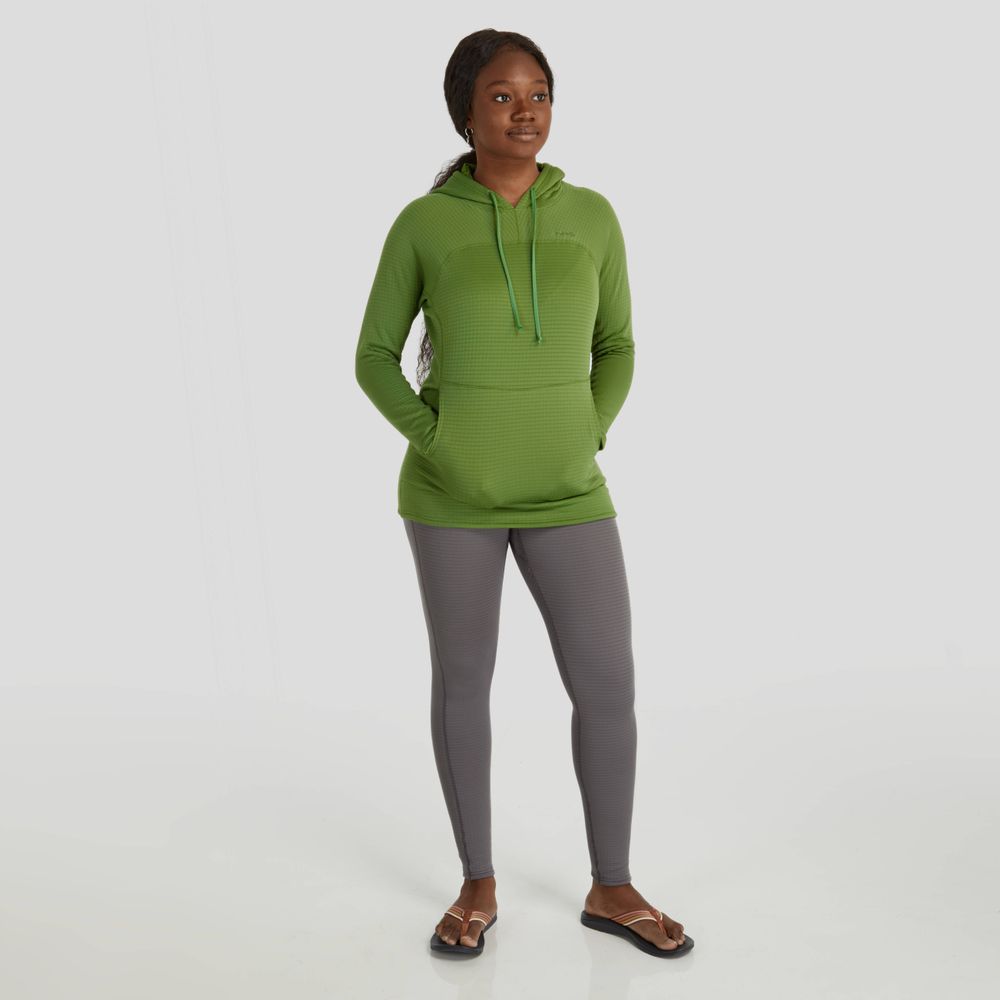 A person wearing an NRS Lightweight Hoodie - Women's in green, made from moisture-wicking fabric, paired with gray leggings and brown sandals, stands against a plain background with hands in pockets.
