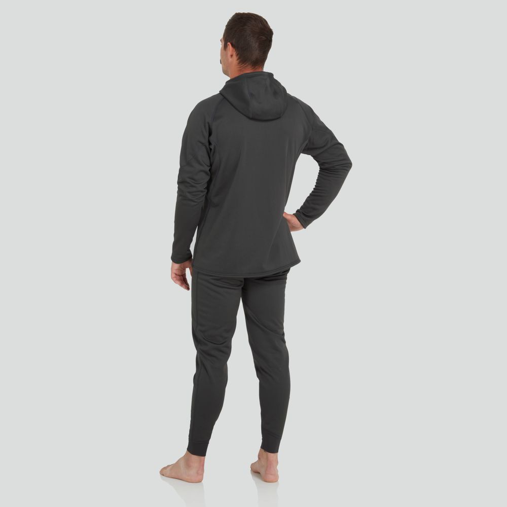 A barefoot individual in a dark NRS Expedition Hoodie for men and high-stretch joggers is seen from behind, facing away with one hand on their hip against a light backdrop.