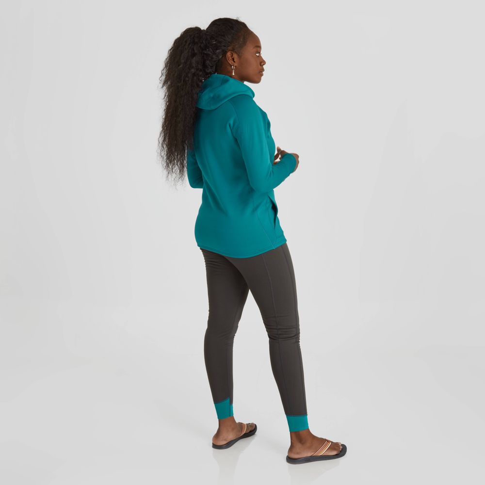 A person stands wearing a teal NRS Expedition Hoodie - Women's, with dark leggings and black sandals against a plain background. The high-stretch fleece offers breathable insulation as they face away from the camera.