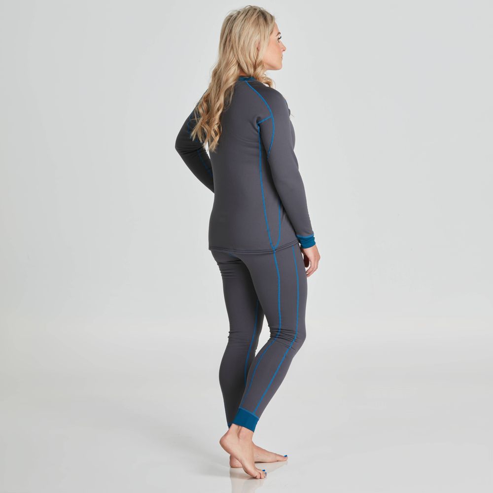 A person poses barefoot against a plain backdrop wearing the form-fitting NRS Expedition Fleece - Women's, a gray and blue long-sleeve athletic outfit made from recycled material.