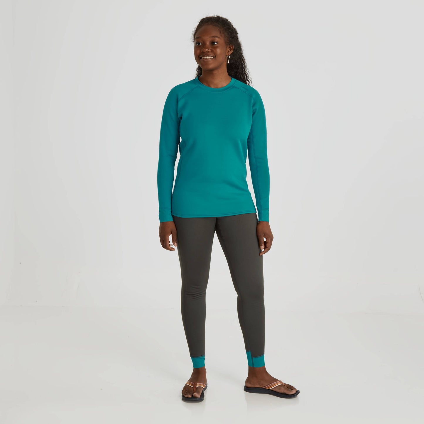 A woman in a teal long-sleeved shirt and grey NRS Expedition Weight Pants - Women's that are versatile and breathable.