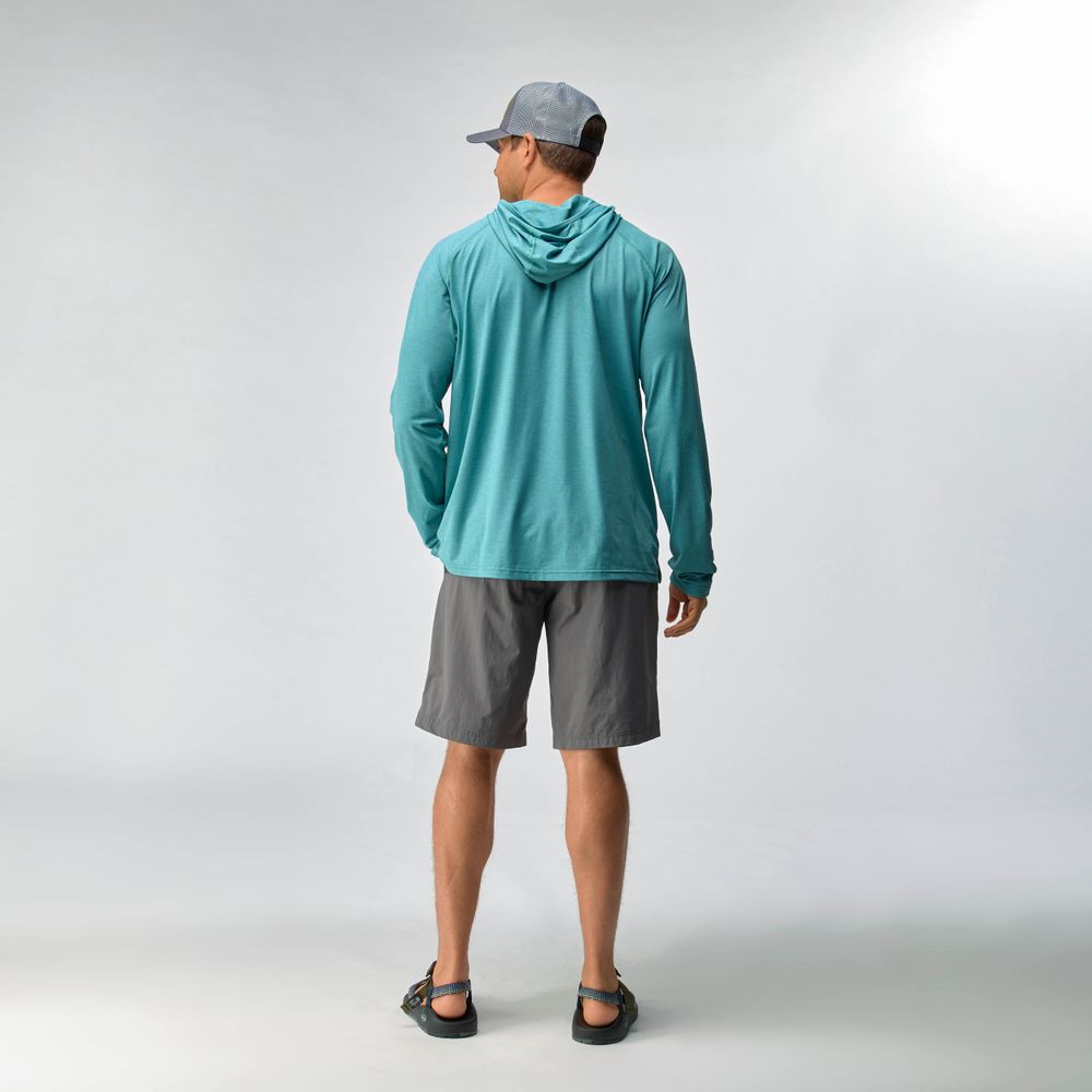 A man faces away wearing the NRS Silkweight Hoodie - Men's in blue, with moisture-wicking fabric, gray shorts, a gray cap, and sandals against a plain light background.