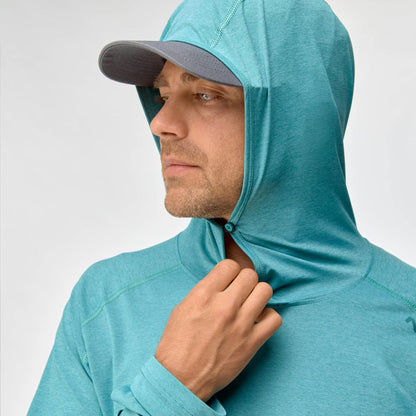 A man wearing the NRS Silkweight Hoodie - Men's in teal and a gray cap looks to the side as he adjusts the zipper, enjoying moisture-wicking comfort and sun protection.