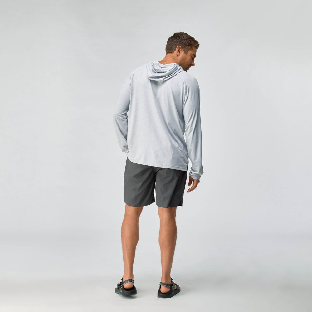 A man faces away, wearing the NRS Silkweight Hoodie - Men's in light gray for sun protection, paired with dark gray shorts and black sandals against a plain light background.