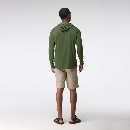 A man faces away, wearing the NRS Silkweight Hoodie - Men's in green for sun protection, along with beige shorts and black sandals, against a plain white background.
