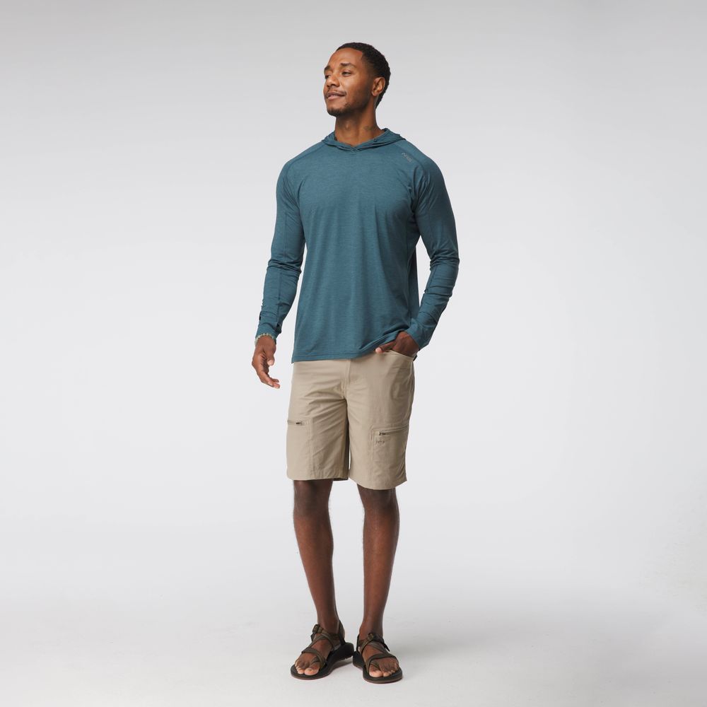 A man stands in a studio wearing the NRS Silkweight Hoodie - Men's for sun protection, paired with beige cargo shorts and brown sandals, set against a plain white background.