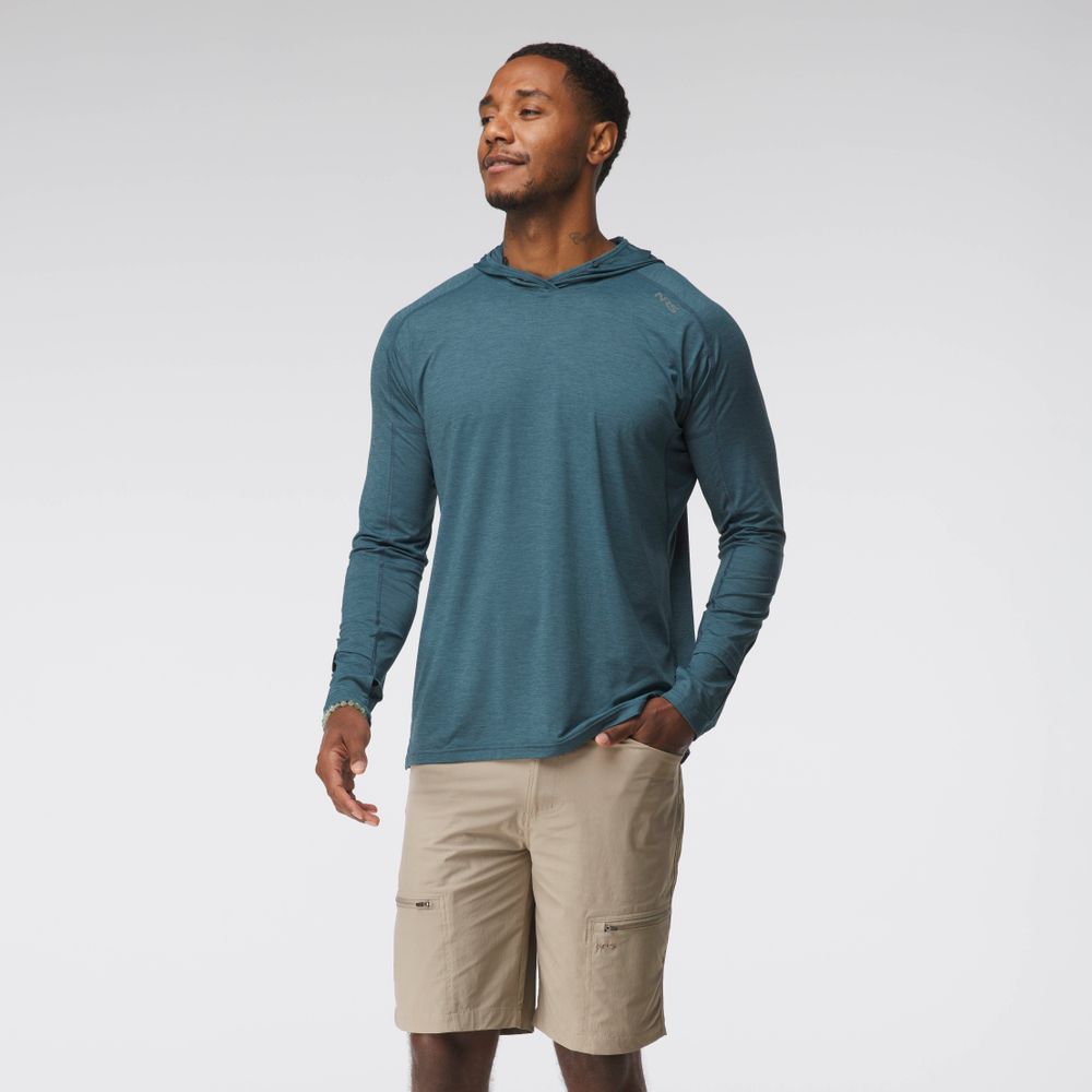 A man stands against a plain background wearing the NRS Silkweight Hoodie - Men's in teal and beige shorts, looking to the side with one hand in his pocket.