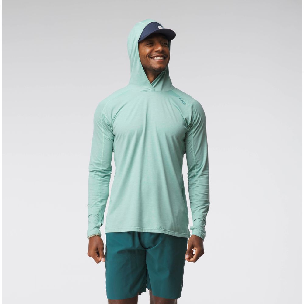 A man smiles against a plain light background, wearing the NRS Silkweight Hoodie - Men's in light green for sun protection, paired with dark green shorts and a navy cap.