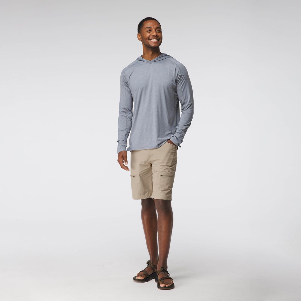 A man stands against a plain background wearing the NRS Silkweight Hoodie - Men's in light gray, paired with beige cargo shorts and sandals.