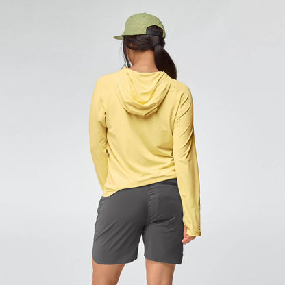 A woman stands with her back to the camera, wearing the NRS Silkweight Hoodie - Women's in yellow for sun protection, a light green cap, and dark gray shorts against a plain light background.