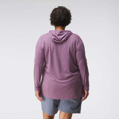 A woman in a purple NRS Silkweight Hoodie and gray shorts stands with her back to the camera against a plain background. The hoodie’s technical fabric provides excellent sun protection, maintaining comfort and style.