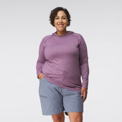 A woman smiles in the NRS Silkweight Hoodie - Women's in purple, offering sun protection, paired with light blue shorts against a plain white background.