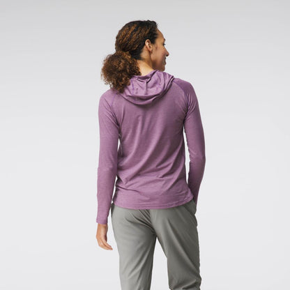 A person with curly hair in an NRS Silkweight Hoodie - Women's in purple and gray pants stands side-view against a plain background. The hoodie's technical fabric offers excellent sun protection.