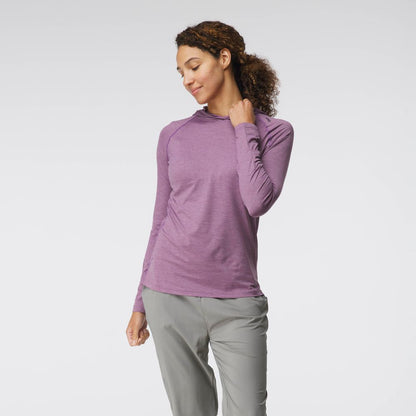A woman models the NRS Silkweight Hoodie - Women's in purple with light gray pants, standing against a white background and touching her collar—ideal as a sun-protective base layer.