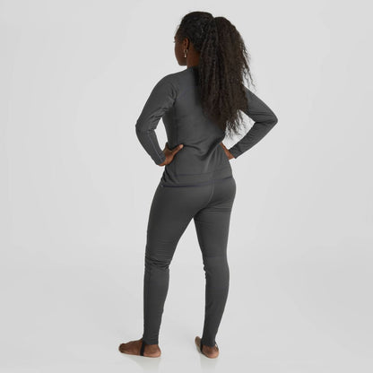 A woman wearing the NRS Expedition Weight Union Suit, a long-sleeve dark gray fleece onesie, stands barefoot on a light gray background, facing away with hands on hips.