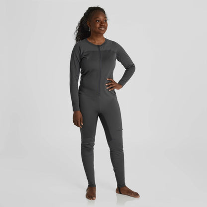 A female paddler confidently wears the NRS Expedition Weight Union Suit for women, a sleek gray full-body suit crafted from recycled materials.