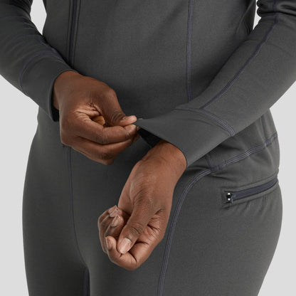 A person adjusts the sleeve of the gray NRS Expedition Weight Union Suit, made from recycled materials, while wearing matching pants with a zippered pocket.