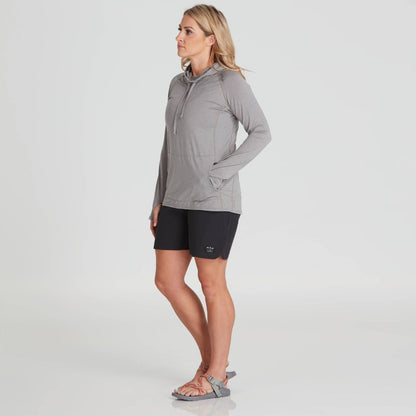 A person wearing the NRS Silkweight Vesi Hoodie - Women's, black shorts, and sandals stands with hands in pockets against a plain backdrop.