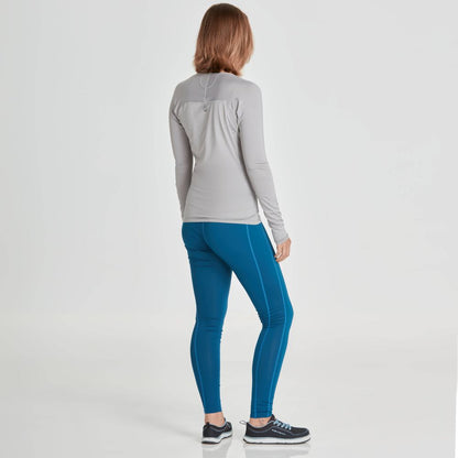 Facing away, a person is wearing a light gray long-sleeve top made from recycled fabric, NRS Ava Rashguard Pants - Women's in blue, and dark sneakers against a plain backdrop.