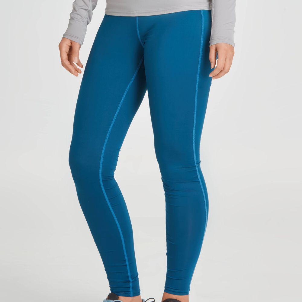 A person is wearing NRS's Ava Rashguard Pants for women, featuring a gray swim tight and blue leggings design. The eco-friendly ensemble provides UPF 50 sun protection and is made from recycled materials, all against a neutral backdrop.