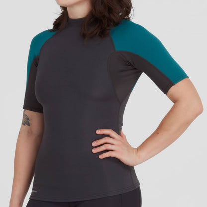 A woman is wearing the NRS Hydroskin 0.5mm Short Sleeve Shirt, posing with one hand on her hip.