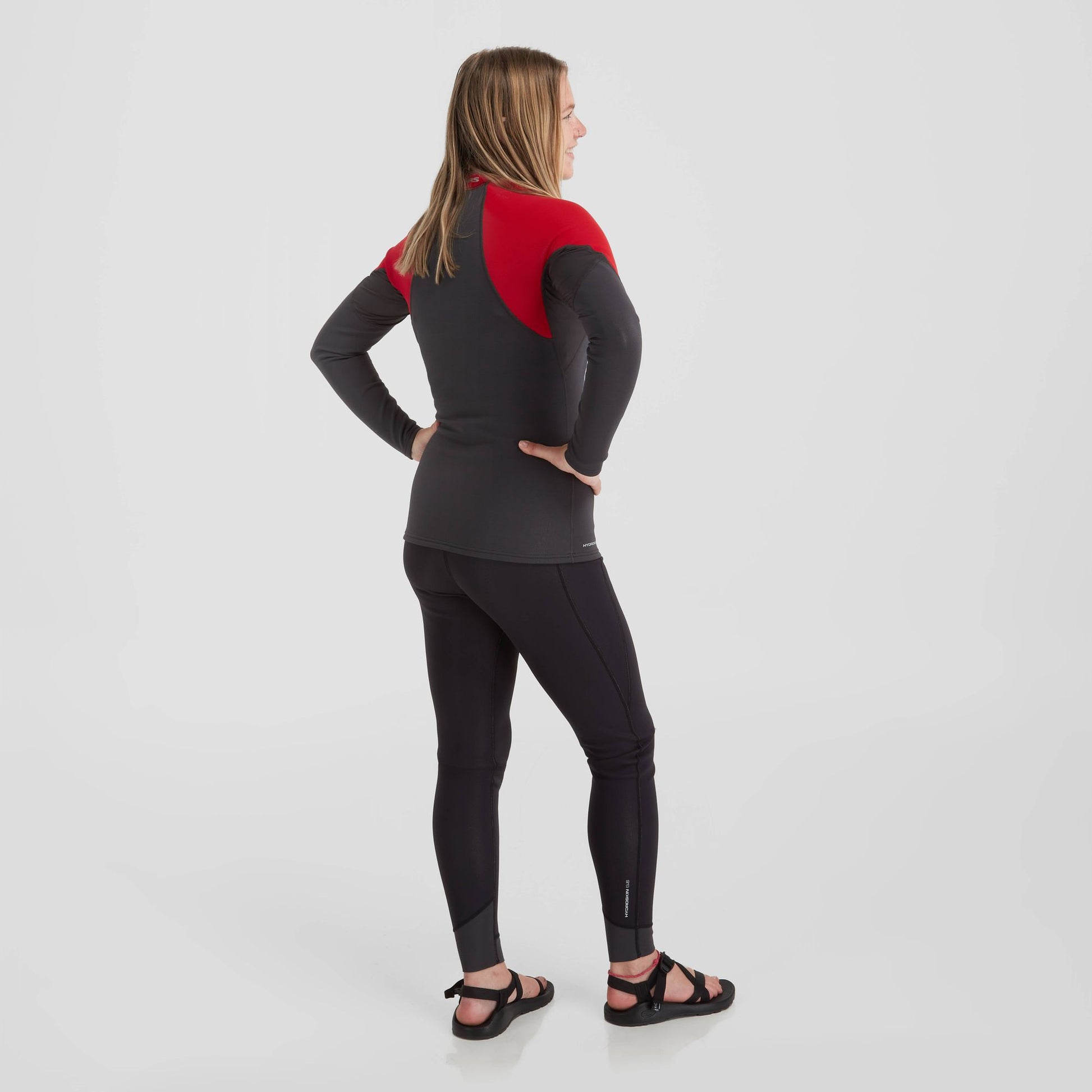 The back view of a woman wearing a NRS Hydroskin 0.5 Long Sleeve Shirt - Women's, an insulating top that is part of her layering arsenal.