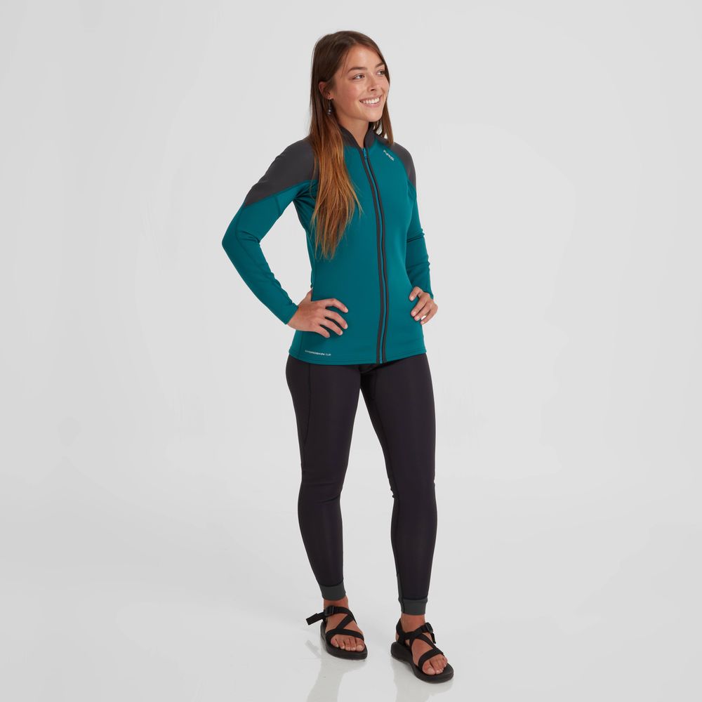 Person wears a teal and black NRS Hydroskin 0.5mm Jacket, black leggings, and sandals on a white background; the neoprene is tailored for optimal paddling performance.