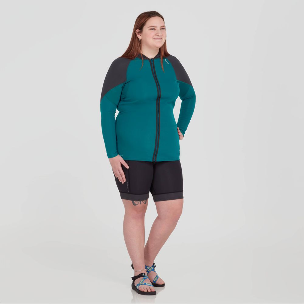 A woman wearing NRS HydroSkin 0.5mm Shorts - Women's, a teal and black hoodie and neoprene shorts.