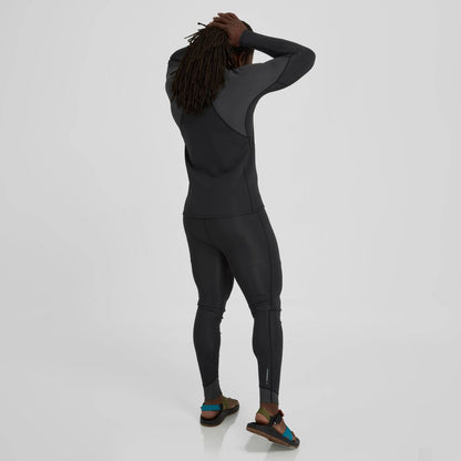 A long-haired person in a dark wetsuit and sandals stands confidently against a light gray background, suggesting superior paddling performance, enhanced by the neoprene insulation of the NRS Hydroskin 1.5mm Jacket for Men.