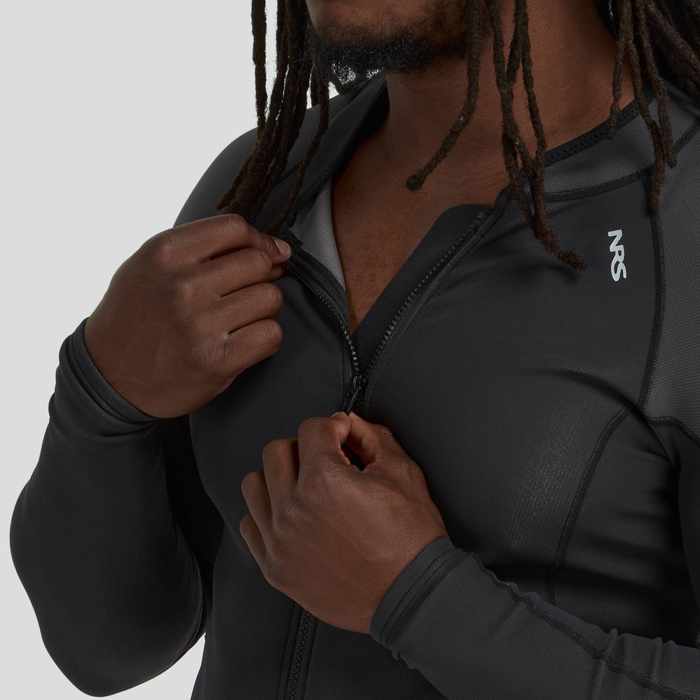 An individual in a black NRS Hydroskin 1.5mm Jacket - Men's, with long sleeves, adjusts the zipper. This jacket is designed for optimal paddling with a logo on the chest and features neoprene insulation for added warmth.
