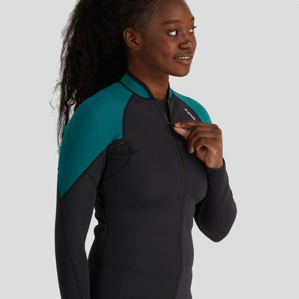 The person smiles warmly, wearing an NRS Hydroskin 1.5mm Jacket - Women's in black with teal shoulders, known for its neoprene insulation that boosts paddling performance, against a neutral background.