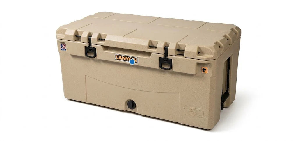 The Canyon Coolers Prospector 150 Raft Cooler is a large tan rotomolded cooler with black latches and handles, a bottom-front drain plug, and Canyon branding—ideal for rugged adventures on the raft.
