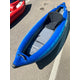 A blue Demo STAR Raven Solo inflatable kayak from NRS, featuring a black seat and gray floor pad, is parked on an asphalt surface next to a red kayak.